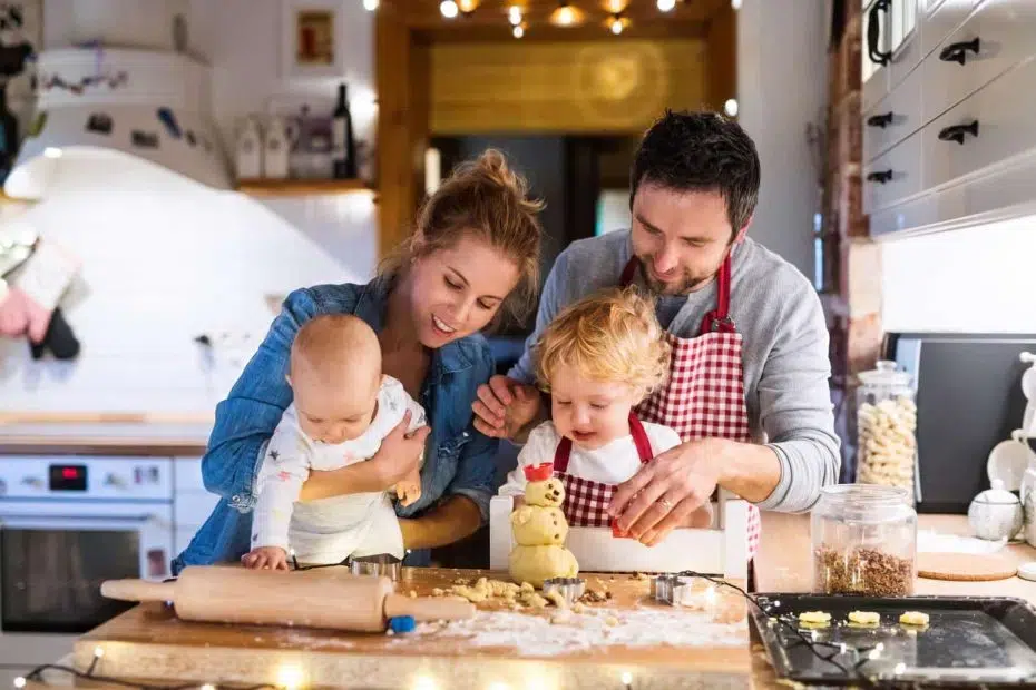 Beautiful young family making cookies at home. Father, mother. toddler boy and baby having fun.